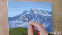 a person is painting a mountain with the words made in animotica below