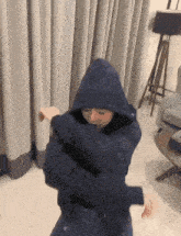a person wearing a hoodie is dancing in a living room .