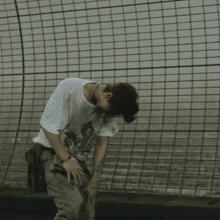 a man wearing a t-shirt that says ' tokyo ' on it is standing in front of a brick wall