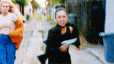 two women are running down a street with one holding a piece of paper .