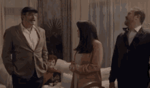 a group of people are standing in a living room talking to each other