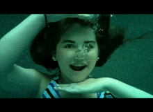a girl in a striped bikini is swimming underwater .