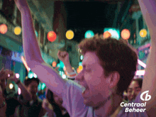 a man with his arms in the air is surrounded by people and a central beheer logo
