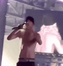 a man without a shirt is singing into a microphone with the number 224 in the lower right corner