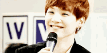 a young man is holding a microphone and smiling