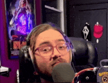 a man with glasses and headphones is talking into a microphone .