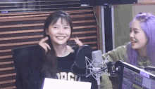 two girls are sitting in front of a microphone in a radio studio .