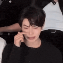 a man is crying while talking on a cell phone in a crowded room .