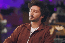 a man with a beard is wearing a brown shirt and a white t-shirt