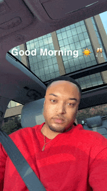 a man in a red sweatshirt is sitting in a car with the words good morning written on the roof