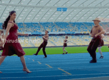a woman in a red dress is dancing on a track in a stadium with thiruda n chat written in the corner