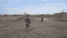 a man in a military uniform is kneeling in the dirt with two children standing behind him