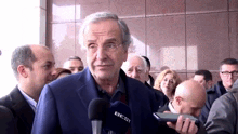 a man in a suit is talking into a microphone that says best on it