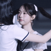 a girl with rhinestones on her face holds another girl 's hair in a ponytail
