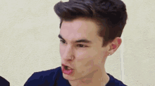 a young man in a blue shirt is making a funny face .