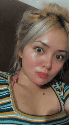 a woman in a striped shirt is taking a selfie