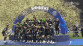 a group of soccer players standing under a sign that says " winners "