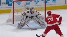 a hockey player with the number 71 on his jersey stands in front of a goalie