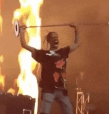 a man is holding a sword in front of a fire while dancing on a stage .