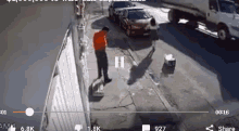 a man in an orange shirt is standing on a sidewalk in front of a white truck