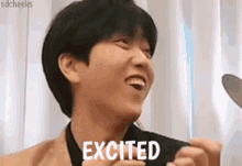 a man is laughing while holding a cell phone and the word excited is on his face .