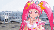 a girl with pink hair is standing on a rooftop with her hands folded