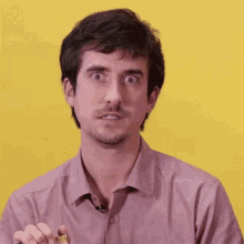 a man in a pink shirt with a microphone on his neck is making a funny face