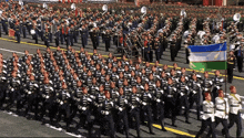 a large group of soldiers marching down a street holding flags