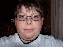 a young boy wearing glasses and a white shirt is taking a selfie