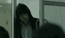 a man wearing glasses and a hooded jacket is standing in a doorway .