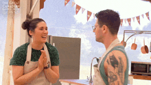 a man and a woman are standing in front of a banner that says the great canadian baking show