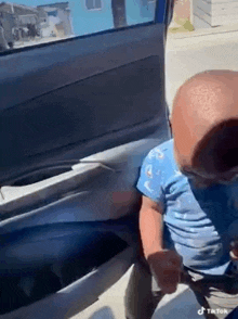 a baby is sitting in the back seat of a car holding a tissue .