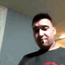 a man is smoking a cigarette while wearing a black shirt .