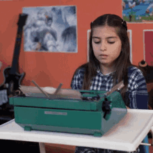 a young girl is typing on a green typewriter in front of a guitar