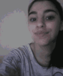 a girl in a purple shirt is taking a selfie and smiling .