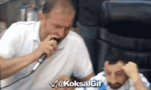 a man is singing into a microphone while another man watches