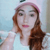 a woman wearing a white shirt and a pink hat with the letter x on it