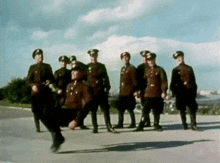 a group of soldiers are standing in a line and one of them is jumping in the air