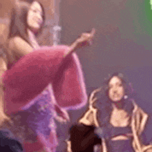 a woman in a pink dress is standing on a stage in front of a green light .