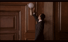 a man in a suit is reaching for a light on a wooden wall