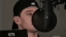 a man is singing into a microphone while wearing a hat .