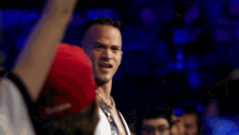 a man in a white shirt and a red hat is standing in front of a crowd of people .