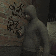 a man in a hooded sweatshirt is standing in front of a brick wall with graffiti on it .
