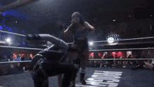 a man and a woman are wrestling in a ring in front of a crowd .