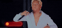 a man in a white shirt is holding a microphone in front of a red button that says gwentealeaves