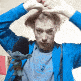 a man in a blue jacket holding a troll doll