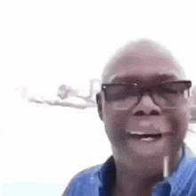 a bald man wearing glasses is smiling for the camera .
