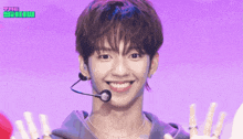 a man with a microphone in his mouth is smiling and giving the middle finger in front of a purple background that says the show