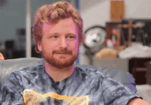 a man with a beard is wearing a tie dye shirt that says cowboy on it