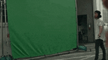 a man wearing a hat is smiling in front of a green screen while taking a selfie .